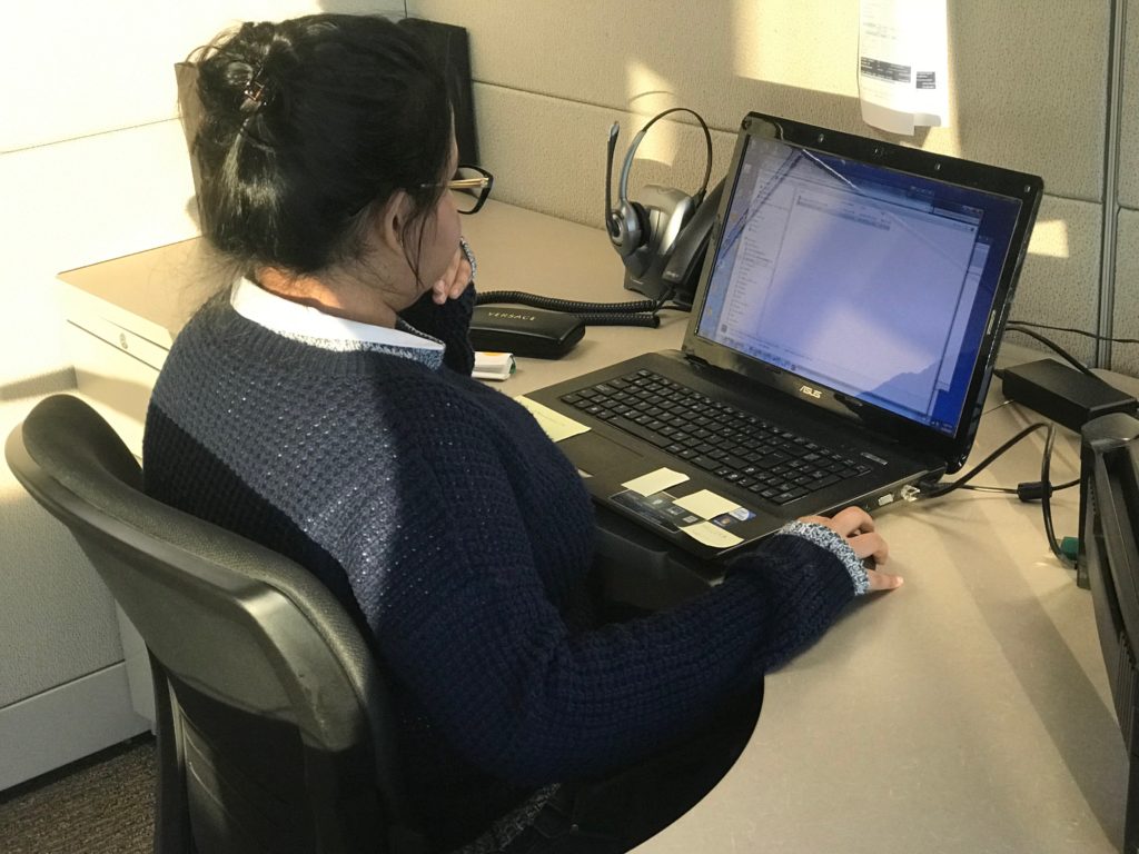 Woman using a laptop in a cubical.