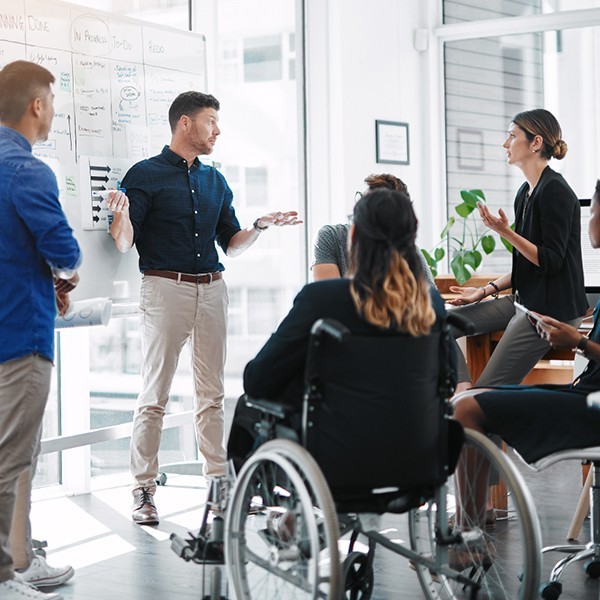 Office coworkers, one in wheelchair, collaborate during meeting