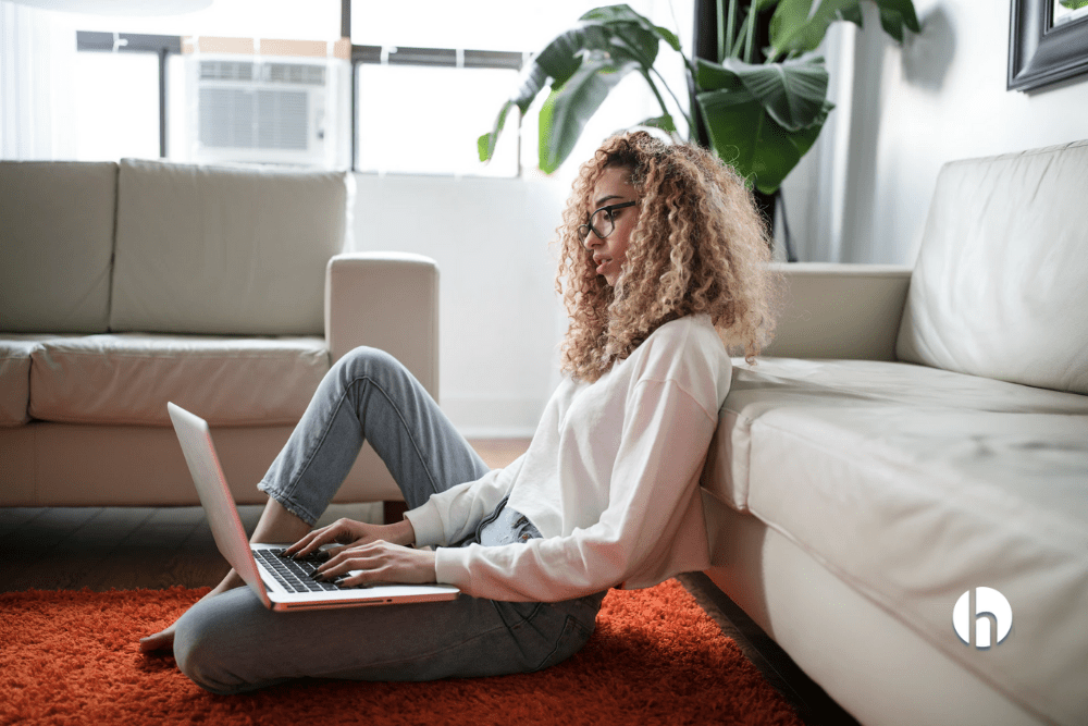Woman sitting on the ground in her living room on a laptop
